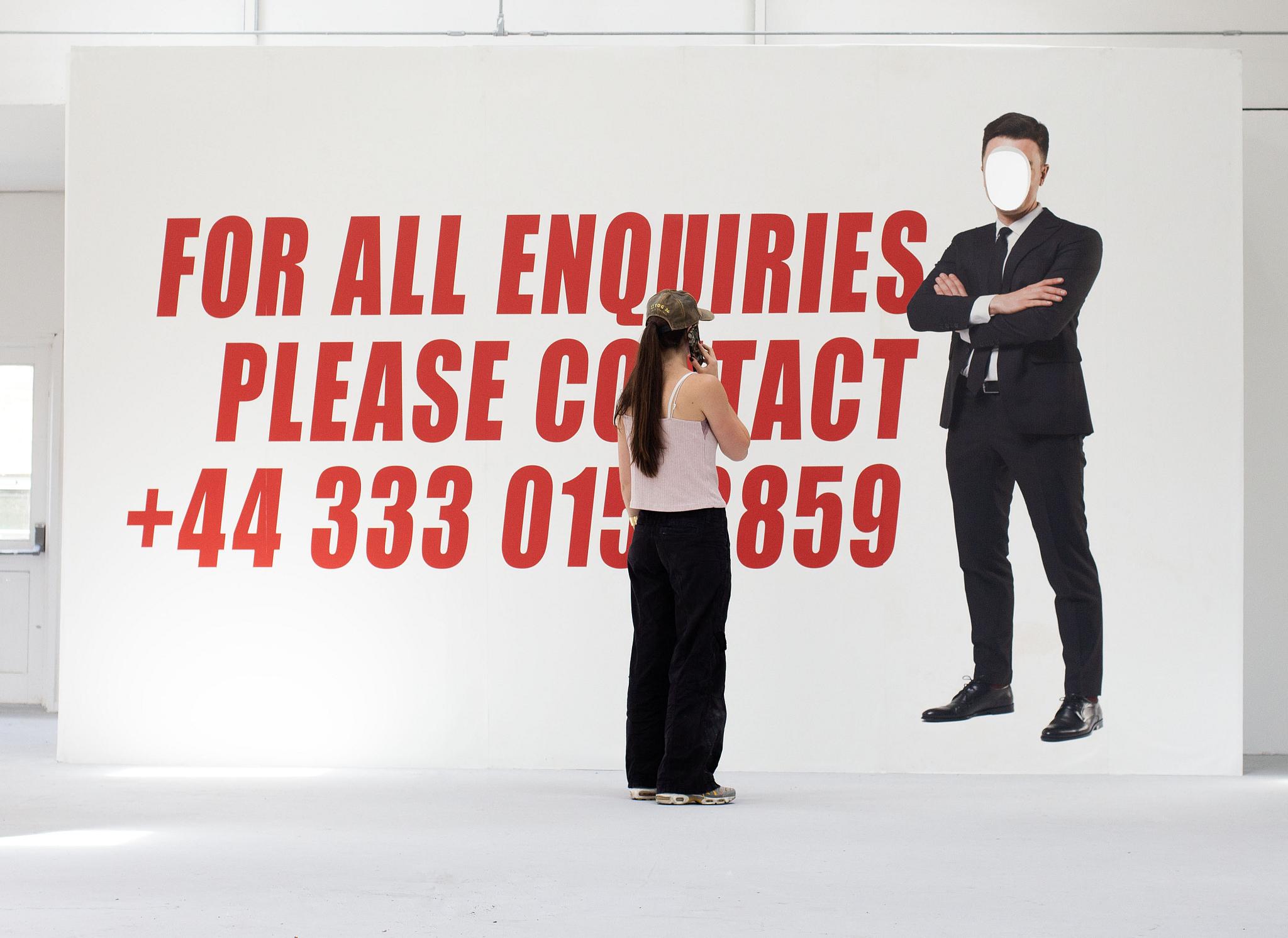 A woman stands in front of a billboard sign, ringing the number advertised